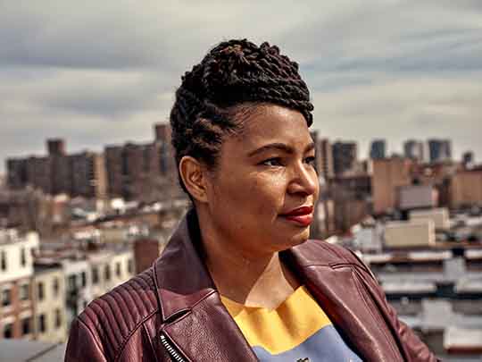 Angela McCrae, owner of Uncorked & Cultured, stands against the New York City skyline.