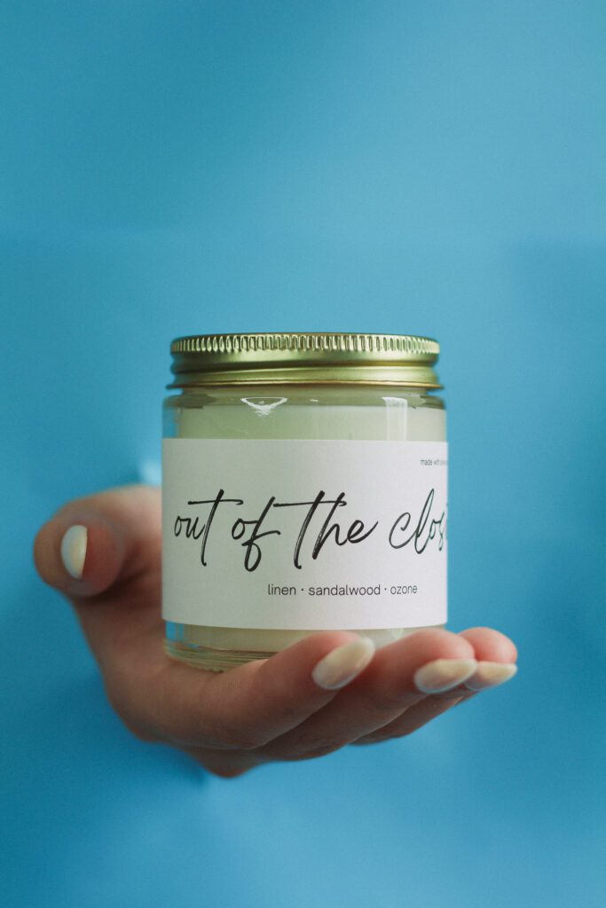 A hand holding "out of the closet" scented candle.
