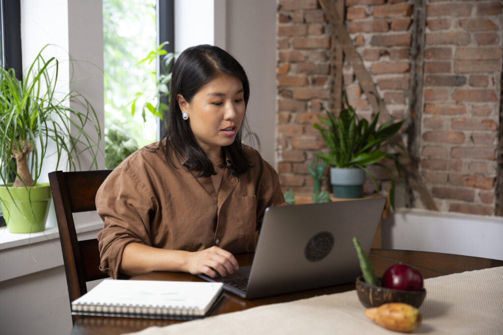 Heather Jiang works with a Block Advisors business professional remotely at a kitchen table after winning a grant for women owned businesses