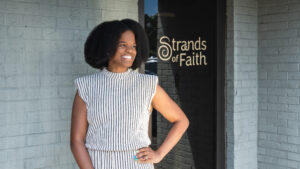 Ameka Coleman, owner of Strands of Faith, stands in front of her storefront. 